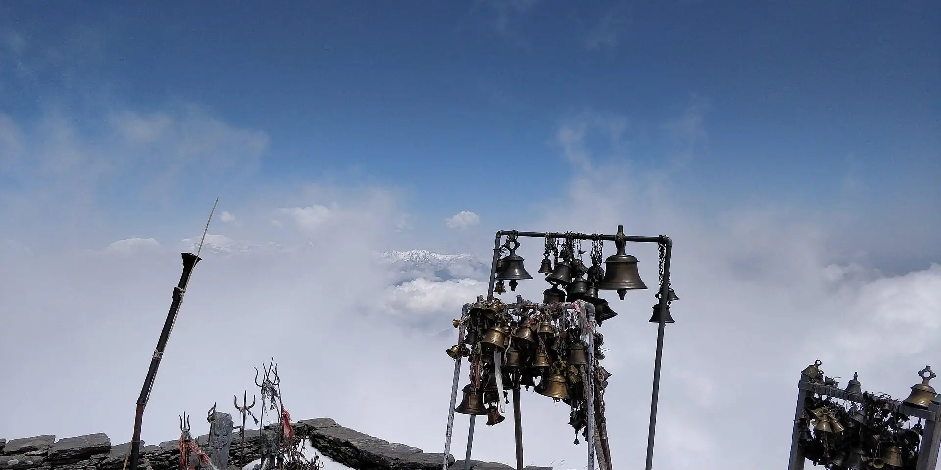 Sacred bells of Badimalika Temple standing above a sea of clouds